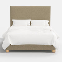 Beige upholstered bed with white bedding on a white background