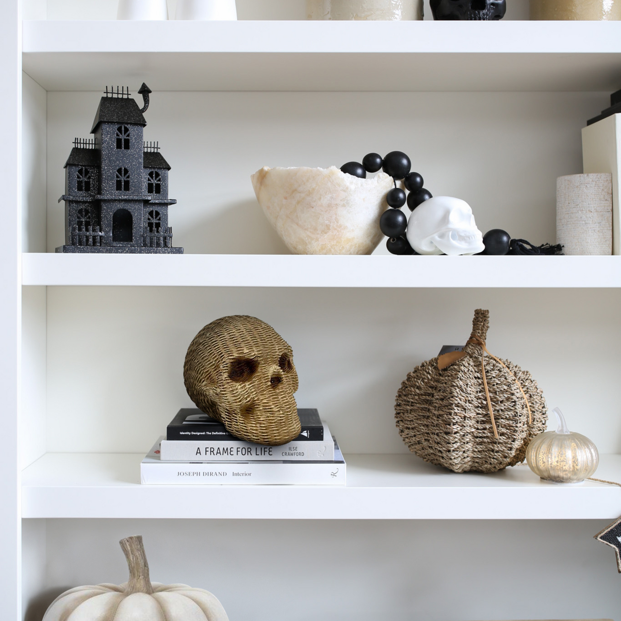 Decorative items on a shelf including a skull, pumpkins, and books.