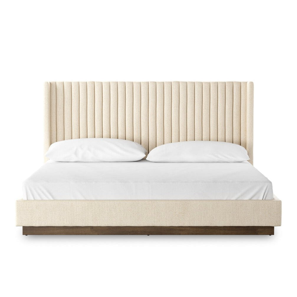 Beige upholstered bed with white bedding on a white background