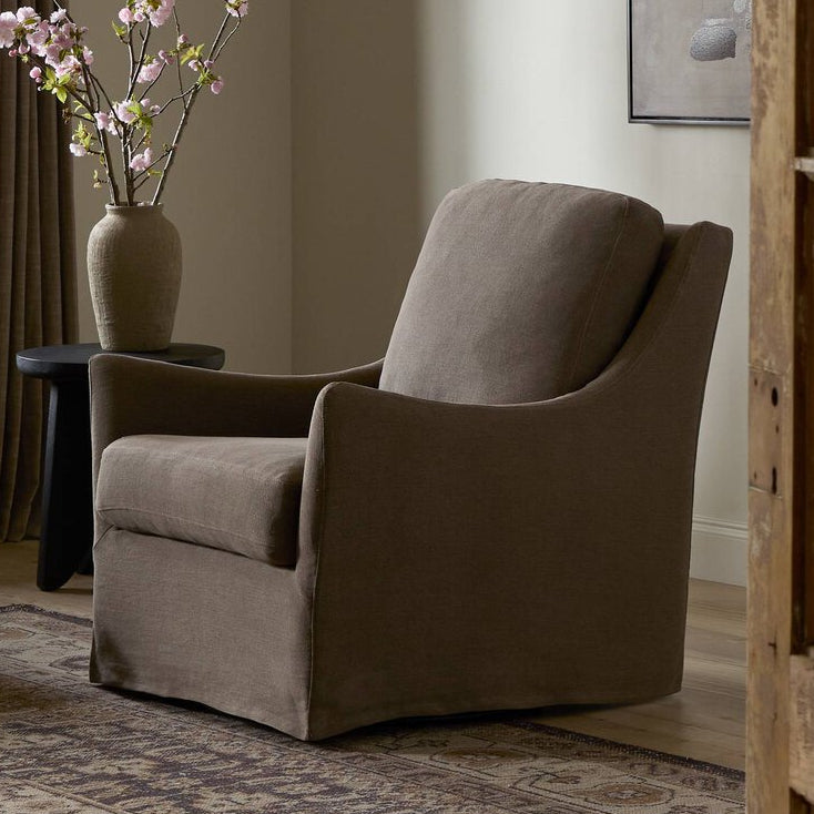 Living room with a gray armchair, coffee table, and decorative vase with flowers.