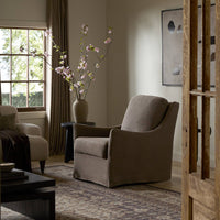 Living room with a gray armchair, coffee table, and decorative vase with flowers.
