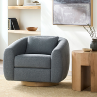 Gray armchair in a modern living room with wooden table and abstract painting.