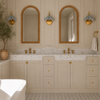 A luxury bathroom interior featuring a double vanity with gold fixtures, arched mirrors, a patterned wallpaper ceiling, and blue-and-white checkered floor tiles.