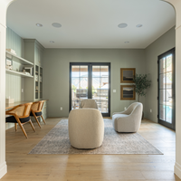 Modern living room with neutral decor, including a sofa, chairs, and a rug.
