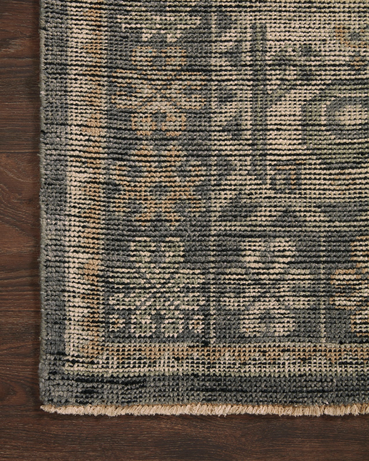 Close-up of a textured rug with geometric pattern on a wooden floor.
