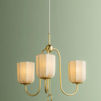 Gold chandelier with three light fixtures against a green wall