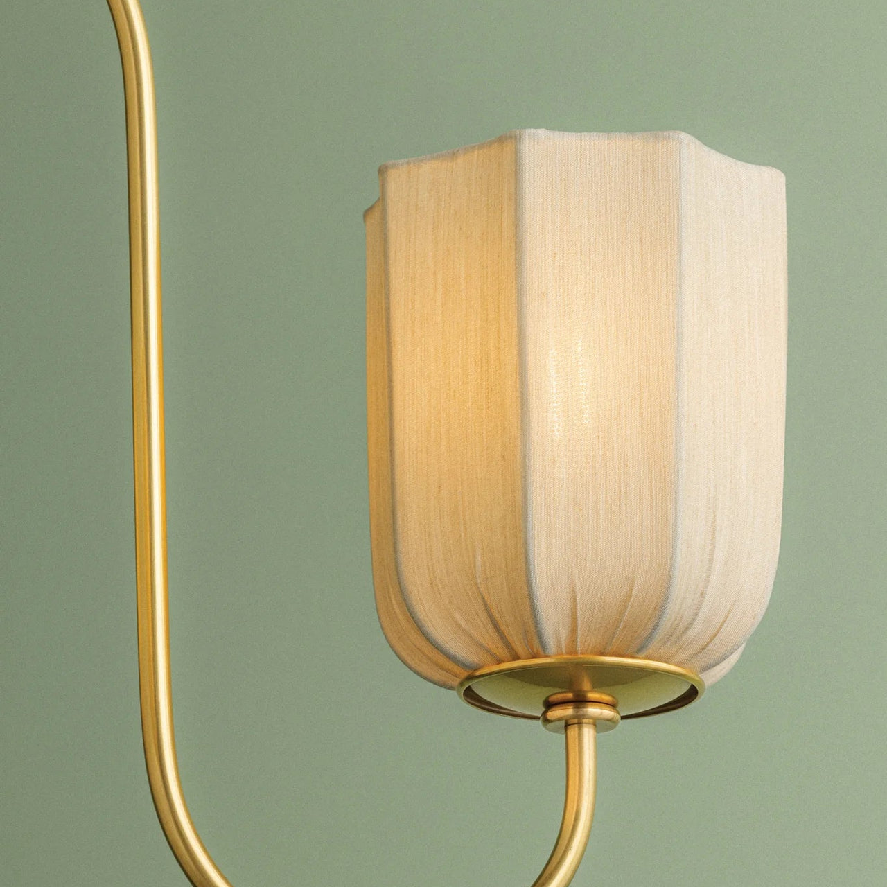 Decorative wall lamp with gold fixture and white shade on a green background