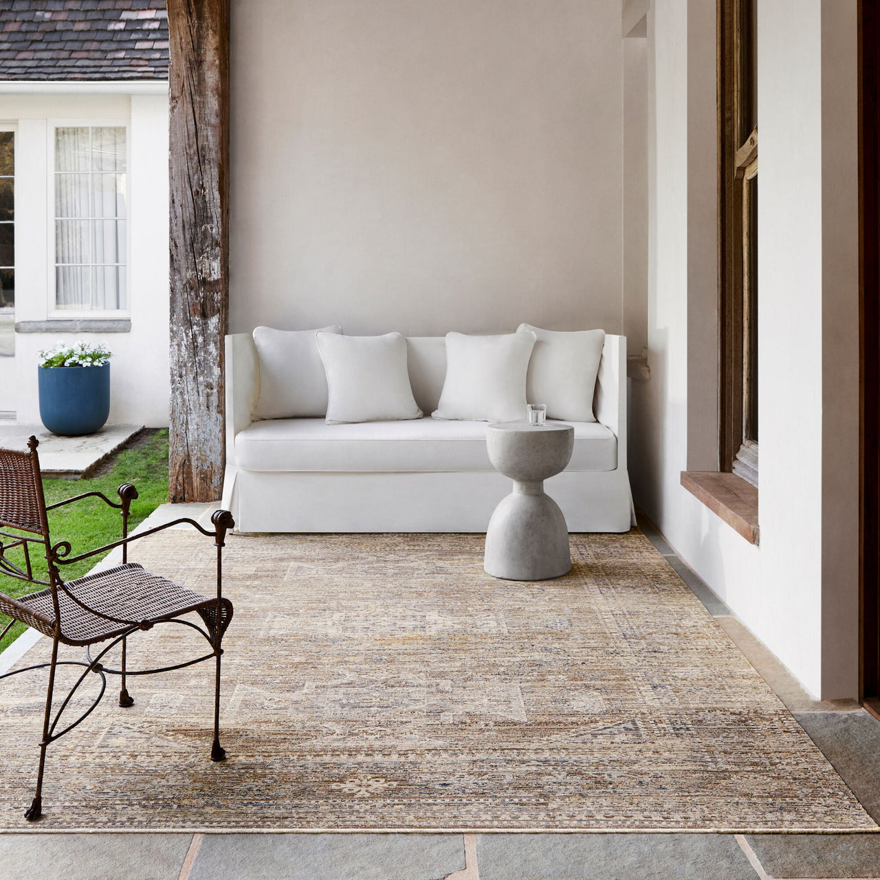 White sofa on a patio with a rug, chair, and decorative elements.