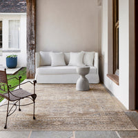 White sofa on a patio with a rug, chair, and decorative elements.